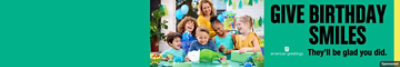 A young boy at his birthday party smiles with friends as he reads his dinosaur birthday card.