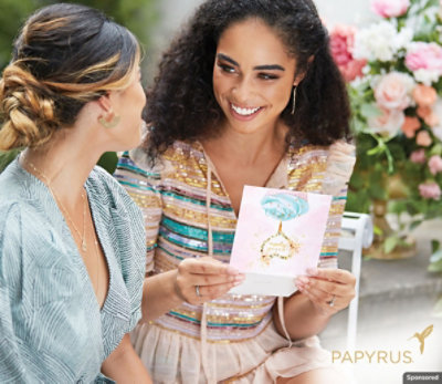 Two women sitting next to each other smiling and holding a birthday card.