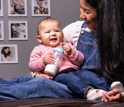 Mommy holding baby on her laps with milk bottle in baby hands