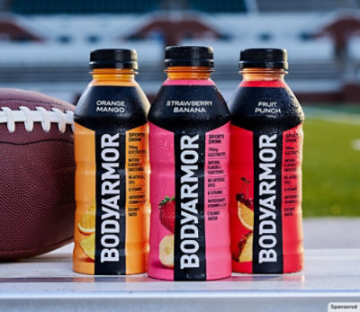 3 BODYARMOR bottles with a football sitting on bleachers.
