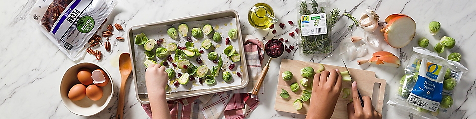 Preparing brussels sprouts and cranberries on a pan for baking.