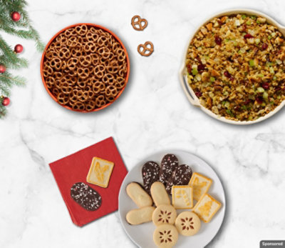 Bowl of pretzels, bowl of stuffing, and a plate of cookies on a white counter.
