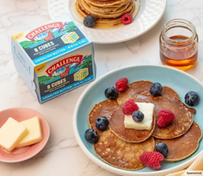 Challenge butter cubes, honey and plates of pancakes on a marble table top. 