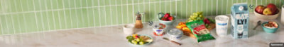Assorted dairy products arranged on a counter for snacking alongside fruits and vegetables.