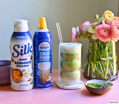 Silk and Cold Foam products with a coffee drink, bowl of matcha powder and vase of fresh flowers.