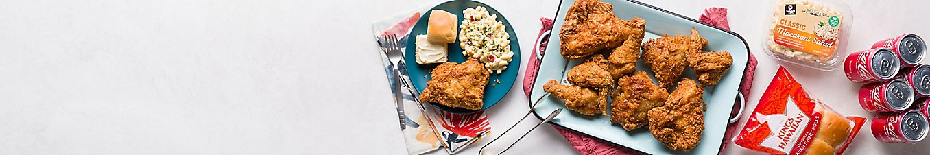 Fried chicken with a side of macaroni salad and King's Hawaiian sweet roll, and cans of Coca-Cola