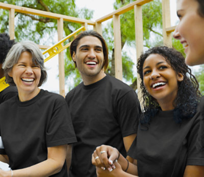 Four people in black shirts laughing outside
