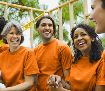 Four people in orange shirts laughing outside