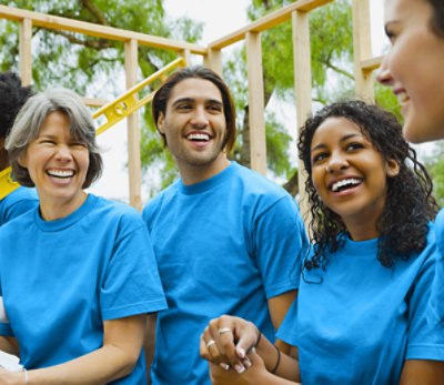 Four people in blue shirts laughing outside