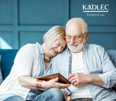Happy couple looking at iPad on couch. Kadlec ExpressCare.