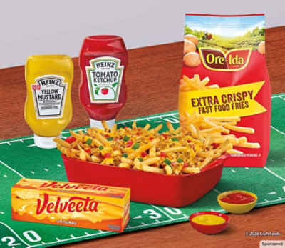 Creamy spinach artichoke dip, chips and Philadelphia cream cheese sit on a football-themed table. 