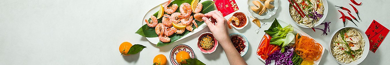 Lunar New Year meal with shrimps, noodles, vegetables, and fortune cookies
