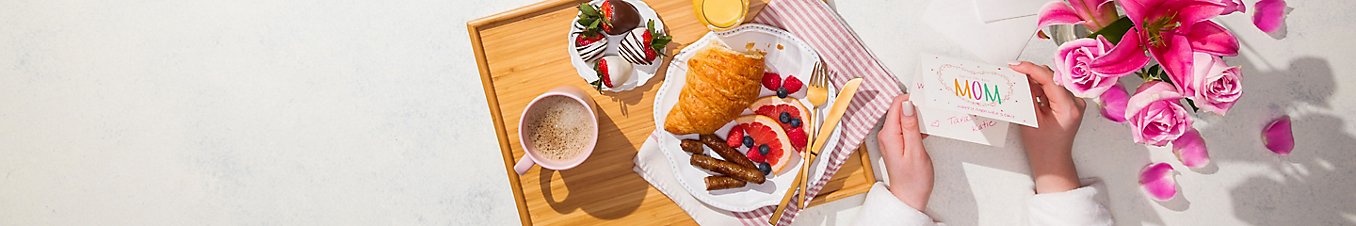 breakfast in bed with pastries, fruit, coffee and flowers
