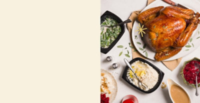 Plates of roasted turkey, green beans, sliced peaches, mashed potatoes with gravy, and cranberry sauce on a table.