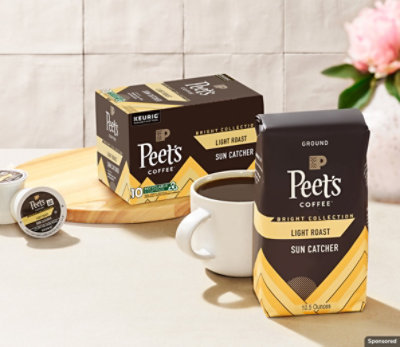 Peet's Sun Catcher pods and grounds on white countertop with filled cup of coffee.