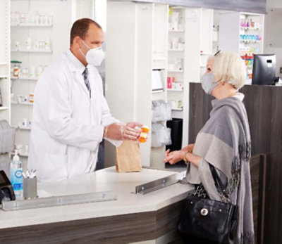 Pharmacist showing medication to patient at pharmacy counter.