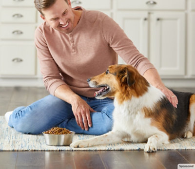Man sitting next to a dog with Nutrish food.