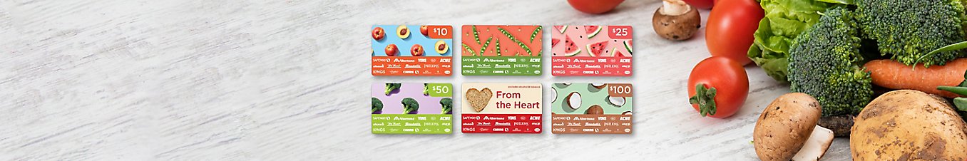 Six giftcards on a table next to a mixed pile of potatoes, tomatoes, carrots, broccoli, mushrooms, and lettuce.