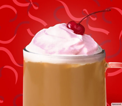A mug of café au lait with cherry almond sweet cream on a red background. 