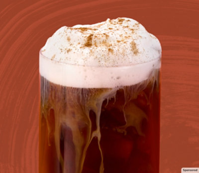 A glass of Starbucks pumpkin spice-flavored brew on a fall-themed background.