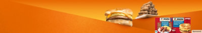 A delicious croissant sausage, egg and cheese sandwich next to a plate stacked with sausage links.
