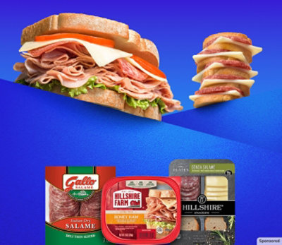 A sandwich piled high with delicious lunch meat and a stack of tasty meat, cheese and crackers.