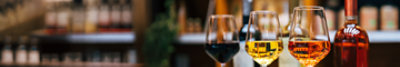 Three glasses of different wine varieties and an un-named bottle of rose in a wine bar setting