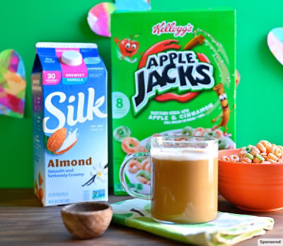 Apple Jacks hot latte with the cereal box and almond milk carton in the back. 