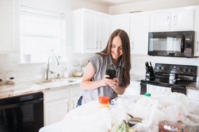 Lifestyle of women unloading Unilever product groceries at home in a white kitchen